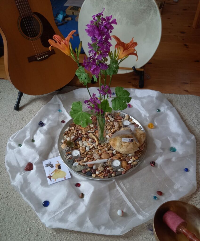 Eine mit Blumen dekorierte Mitte, Gitarre und Trommel für die Chanting Singgruppe.
