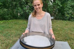 Eine große runde Ocean Drum wird von Elena Deppe in beiden Händen gehalten und gepielt.